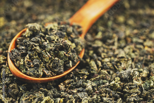 Green oolong tea scoop on flat background wooden spoon macro