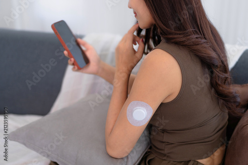 Asian woman using continuous glucose monitoring system at home