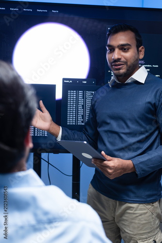 Programmer team collaboration, working on coding task, reviewing code while Male Programmer presenting code in the screen in tech office.