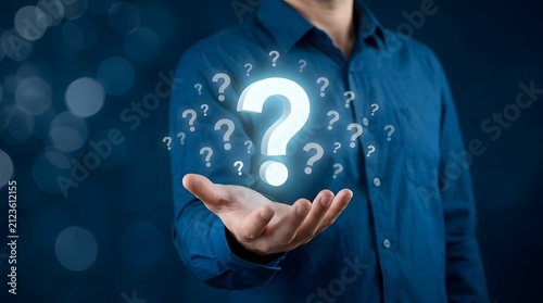 A businessman holding a glowing digital question mark icon in his hand representing business problem solving and decision making concepts
