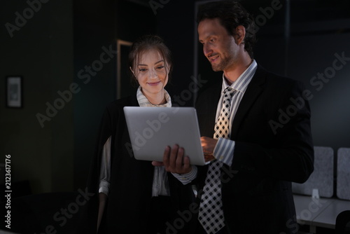 Fotografía Manager keeps talking through the numbers as the young woman tilts the laptop toward herself, faint chairs and desks emerging behind the night pair in a bright modern coworking office