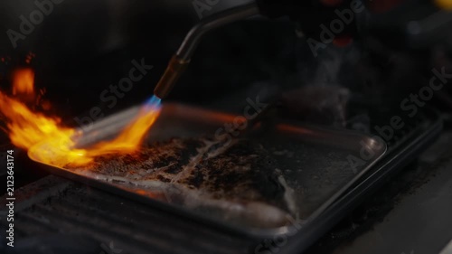 Chef uses torch to caramelize sugar on dessert in a restaurant kitchen