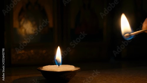 Hand lighting a candle with a matchstick in the dark