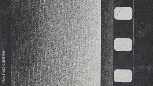 Vintage black and white film strip with prominent sprocket holes and heavy grunge texture. Abstract distressed analog photography background with dust and grain