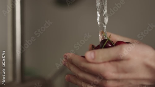 Slow motion closeup shot of man washing cherries with kitchen faucet