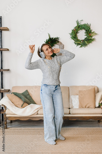 Woman listening music headphones dancing living room Christmas