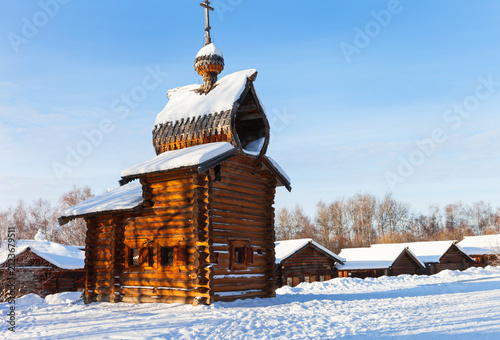 Travels to historical Taltsy village in winter holidays. View of wooden chapel of Kazan Church 1679 at sunny cold December day. Architectural ethnographic museum - popular landmark of Irkutsk region