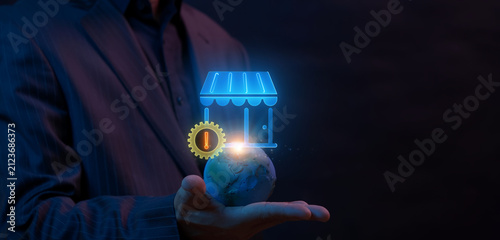 Fotografie Hands holding world globe with storefront shop and gear wheel containing exclamation mark warning icon