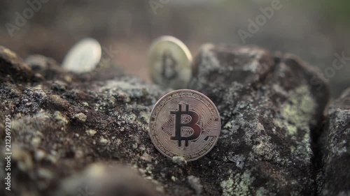 Gold Bitcoin coins resting on rocky ground with a dry, barren landscape in the background, representing cryptocurrency, blockchain, digital assets, fintech, and modern investment.