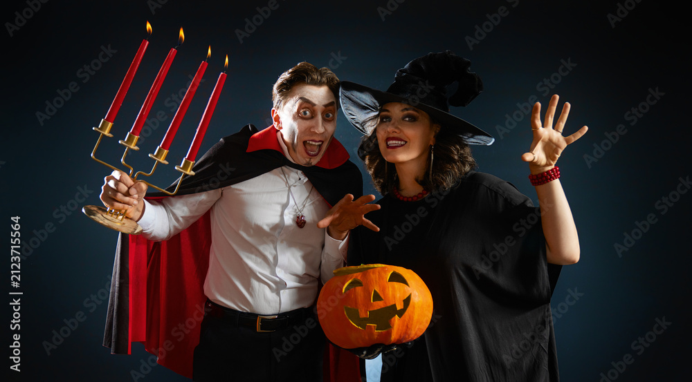 Obraz premium Happy Couple in Halloween Costumes with Pumpkin, Dracula and Witch
