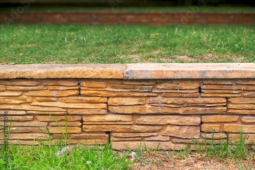 Close-up of stone retaining wall with stacked stone veneer cladding in public park garden landscaping