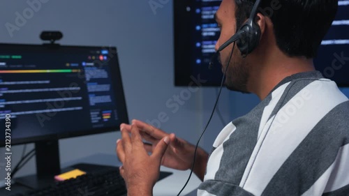 Indian Male IT Support Agent, Technical Help Desk, Customer Service, Remote Assistance, Headset Communication, Problem Solving sit at desk in Call Center Office.