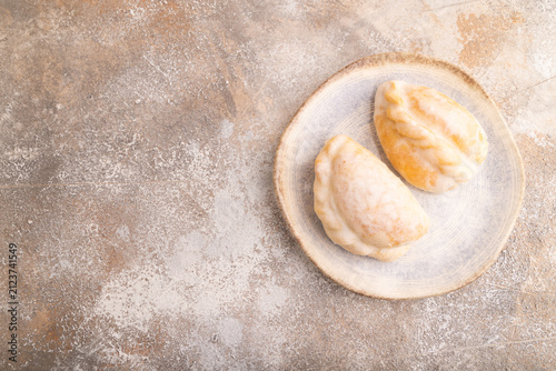 Glazed Pies with blueberry jam on brown concrete, top view, flat lay, copy space