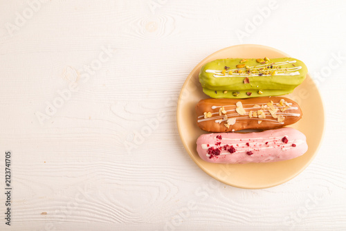 Glazed Eclairs on white wooden, top view, flat lay, copy space