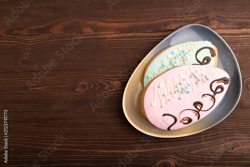 Glazed pink and blue decorated cookies on brown wooden, copy space, top view