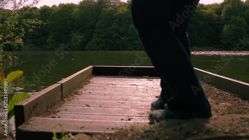 Hiker walks on wooden boardwalk to enjoy view of lake
