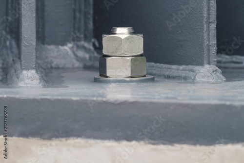 close-up of high-strength steel anchor bolts and heavy hex nuts fastening structural steel column to concrete foundation, steel construction, structural engineering, infrastructure, building assembly