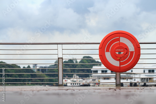 lifebuoy by river for rescue in emergency on cloudy day, floating rescue tool thrown to a person in the water to stop them from sinking, shallow depth of field, copy space