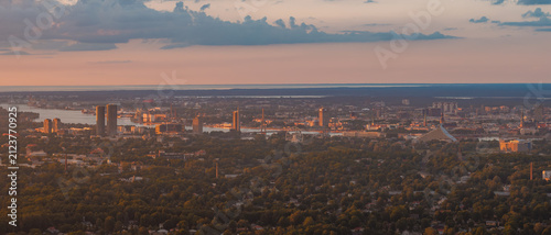Panoramic aerial view of the town of Marupe stretching towards the distant skyline of Riga and the Gulf of Riga beyond, at sunset. Marupe, Latvia.