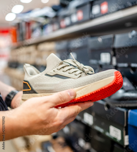Hand holding sneaker in shoe store