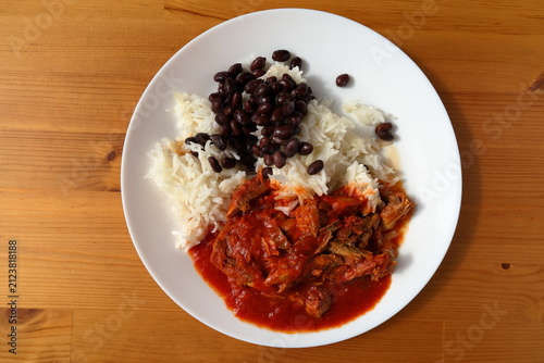 Plate with food. Mackerel in tomato sauce, rice and black beans.