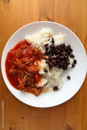 Plate with food. Mackerel in tomato sauce, rice and black beans.