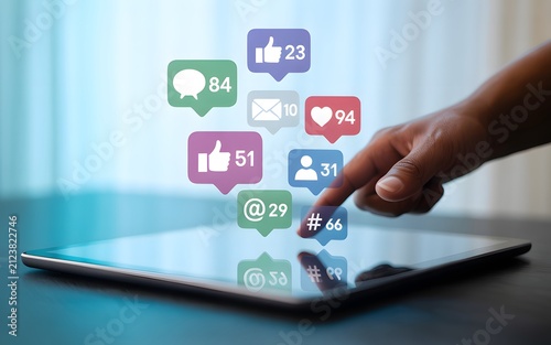 Hand touching tablet screen with colorful social media and notification icons floating above.