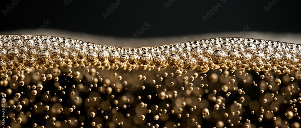 Obraz premium Opulent celebration concept extreme macro of champagne bubbles rising to a shimmering golden surface against a dark backdrop. Perfect for premium beverage, event, or luxury lifestyle.