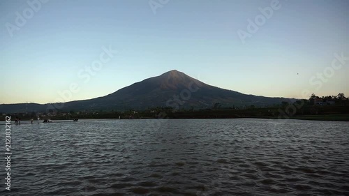 Majestic view of Mount Cikuray in Garut with a calm lake water surface in the afternoon.	