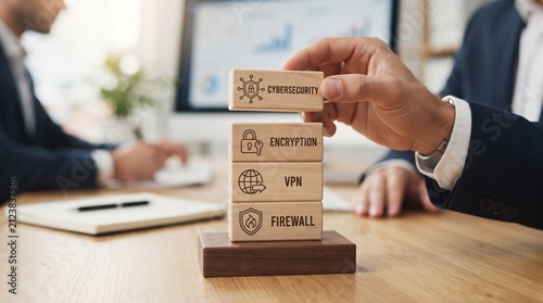 Hand stacking wooden blocks with icons representing cybersecurity encryption VPN and firewall concepts on office desk