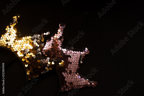 top view of two strips of a crown with shiny confetti on a black background