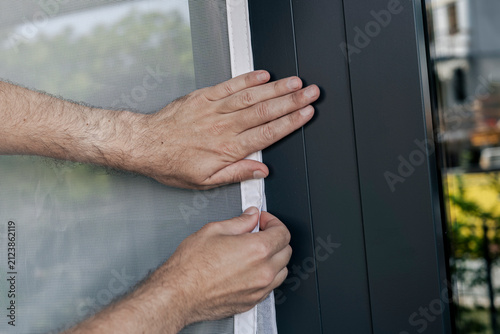 Obraz na płótnie White mosquito screen being pressed onto hook and loop tape on a window frame, showcasing home maintenance and household work