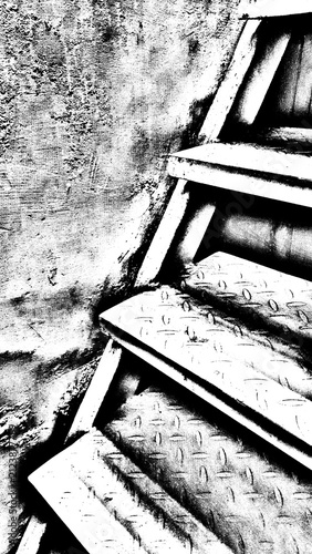 High-contrast black and white grunge abstract background of industrial metal staircase stairs with checkered diamond plate texture near old wall.