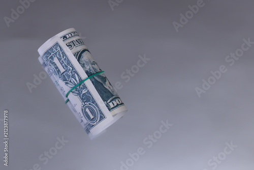 Quadro su tela Rolled one dollar bill tied with a rubber band lying on a mirror.
