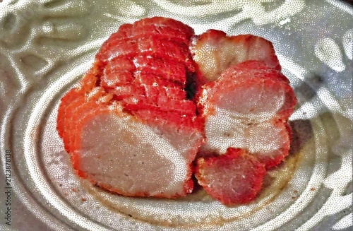 Sliced Chinese BBQ pork char siu with distinctive red outer layer served on a plate.