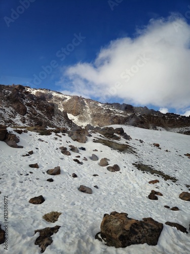 Snowy mountain slope with rocky terrain and blue sky