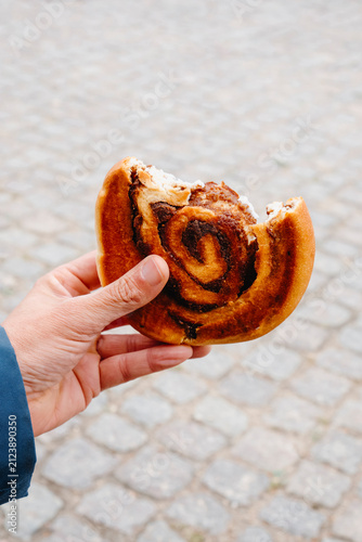 a man holding a bitten danish kanelsnegl