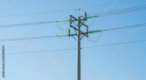 A concrete utility pole with power lines against a clear blue sky