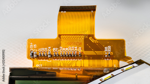 Flexible printed circuit, mobile or tablet LCD screen and interface with LED diodes for backlight. Flex connector and electronic components for surface mount on plastic membrane with white background.