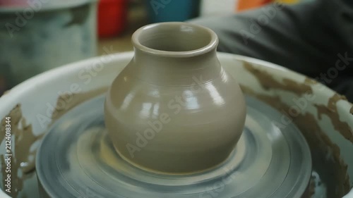 Potter shaping clay vase on a pottery wheel