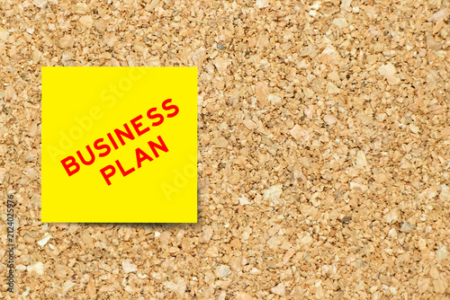 Yellow note paper with word business plan on cork board background with copy space