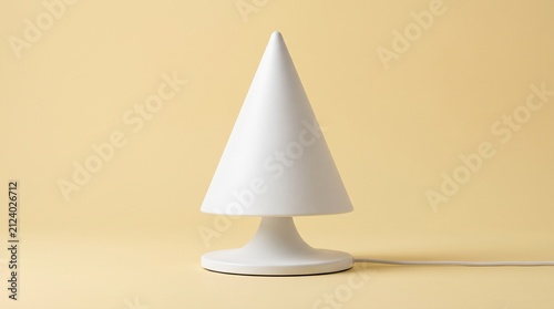A modern white conical table lamp with a flared base, set against a smooth pastel yellow background in a minimalist studio setup.