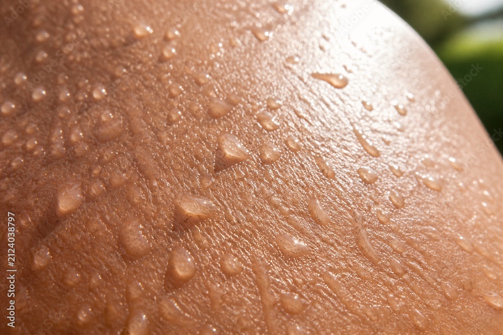 Fototapeta premium Human skin with water droplets macro close up under sunlight