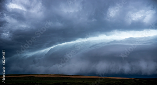 Canvastavla Dramatic landscape featuring a massive shelf cloud of a supercell thunderstorm moving over a rural road and countryside fields, capturing the powerful atmosphere of an approaching storm