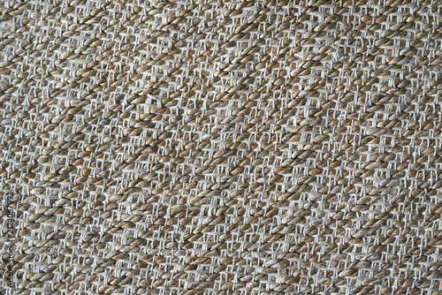 Macro background texture of a rough woven fabric material with neutral beige, brown, and grey colored threads.