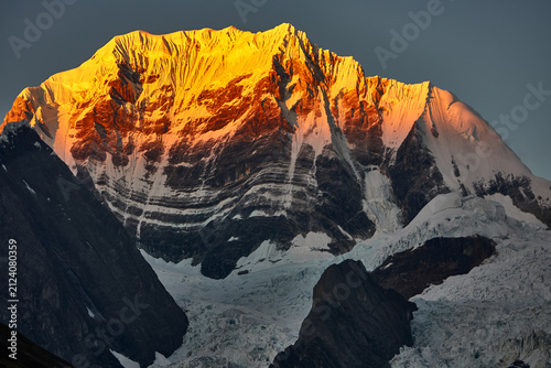 Foto the legendary east face of Siula Grande, the Cordillera Huayhuash awakens in a breathtaking display of golden light, towering ice walls, and rugged alpine beauty