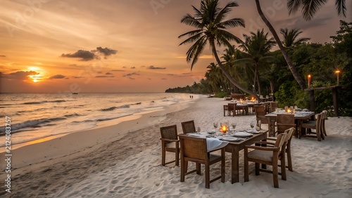Sunset beachside dining tables set under palm trees by ocean waves