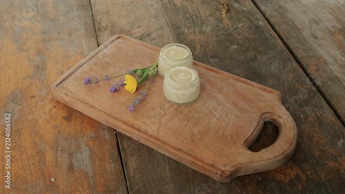neutral wooden cutting board with candles and flowers on a rustic surface, captured from a top-down view.
