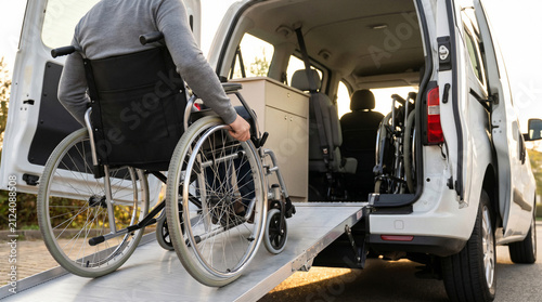 Disabled person in wheelchair entering an adapted van by accessibility ramp for representing inclusive transportation, personal independence, mobility and assisted travel.