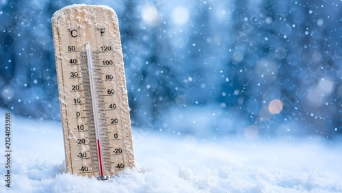 Wooden Thermometer Showing Below Freezing Sub-Zero Temperature Standing in Snow During Heavy Winter Snowfall